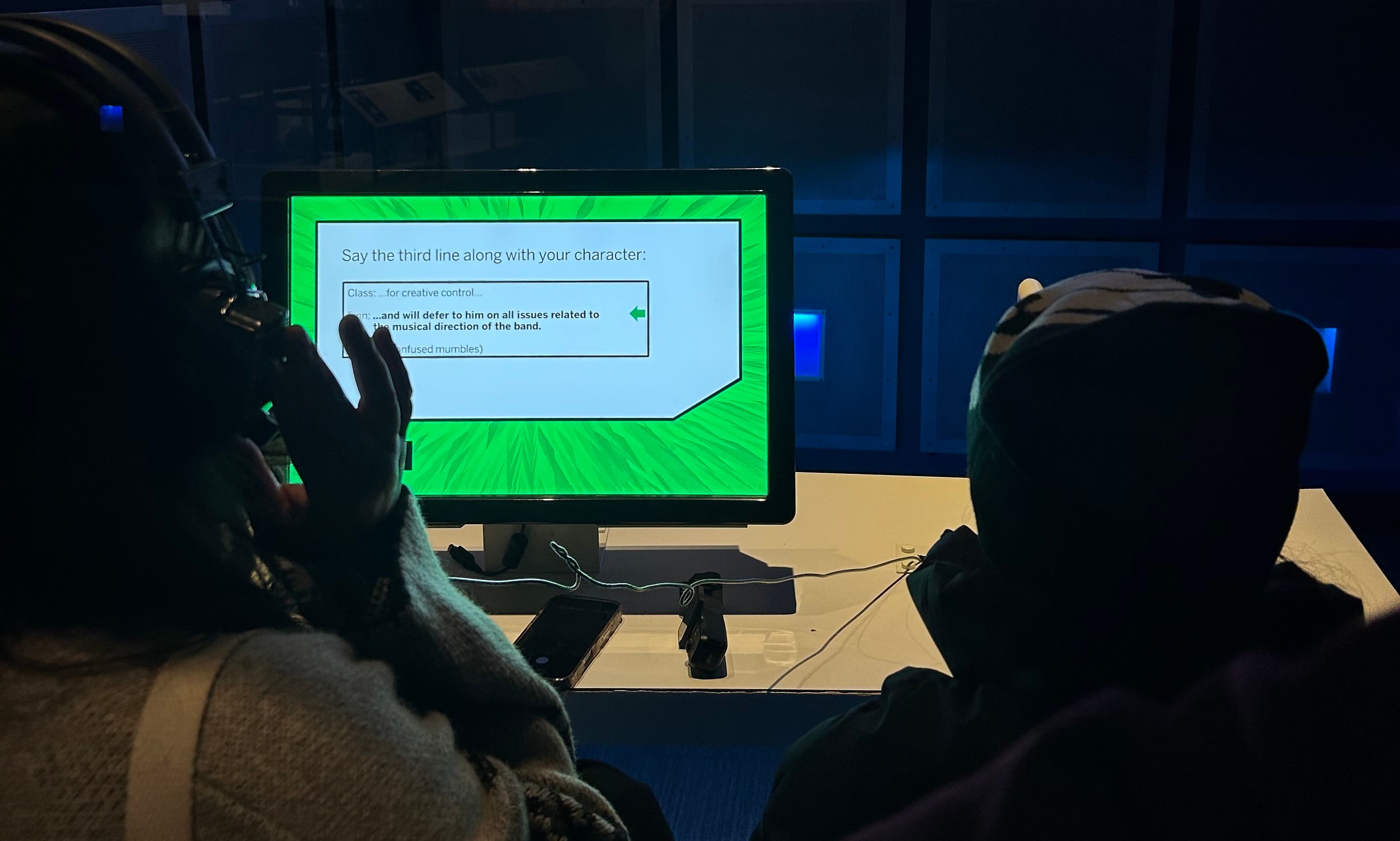 Visitors of all ages exploring an interactive museum exhibit on a wall of large touchscreens.